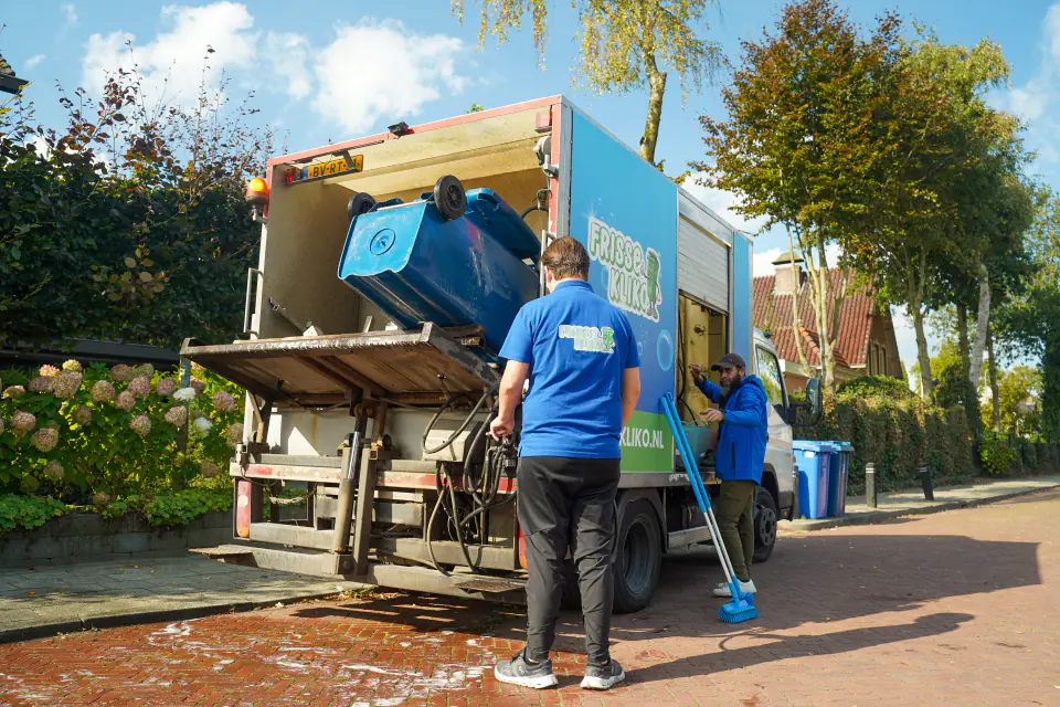 Twee medewerkers laden een container in de reinigingswagen van Frisse Kliko.